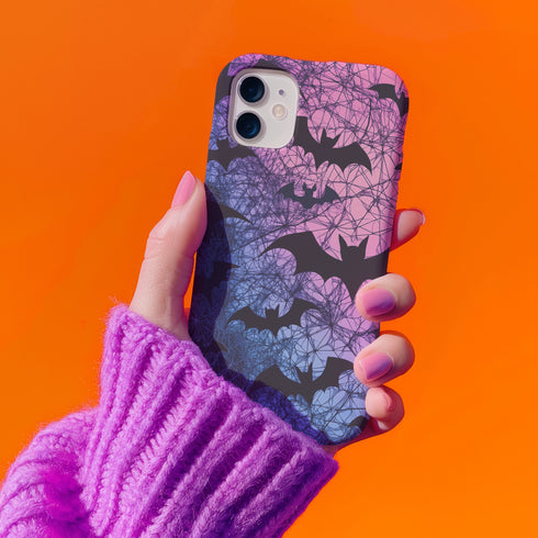 A pastel gothic phone case featuring black bat silhouettes over a gradient pink-to-blue ombré background with web-like detailing. Available for iPhone, Samsung, and Google Pixel models in matte or glossy finishes with dual-layer protection.