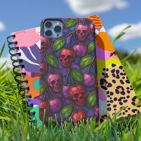 A protective phone case with a gothic cherry skull design featuring red and pink skulls blended with purple cherries and vibrant green leaves. The pattern is outlined in gold and set against a deep blue-purple stained glass background. The case has a smooth matte finish and fits various phone models with precision-cut camera openings.