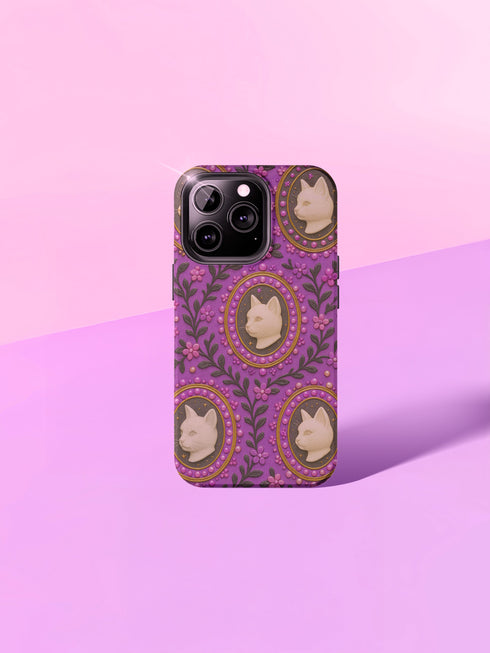 Pastel goth phone case with baroque cameo-style white cat heads framed by pearls and purple florals on a violet background; available for iPhone, Samsung, and Pixel models