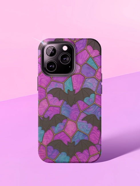 A protective phone case featuring a stained glass-style design in shades of purple, blue, and pink, with black bats flying across geometric panels outlined in gold. The case has a smooth matte finish and fits a triple-camera smartphone model.