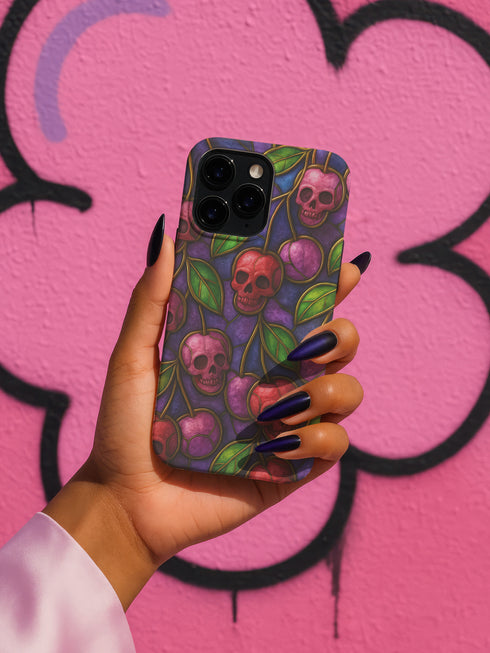 A protective phone case with a gothic cherry skull design featuring red and pink skulls blended with purple cherries and vibrant green leaves. The pattern is outlined in gold and set against a deep blue-purple stained glass background. The case has a smooth matte finish and fits various phone models with precision-cut camera openings.