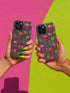 A protective phone case with a gothic cherry skull design featuring red and pink skulls blended with purple cherries and vibrant green leaves. The pattern is outlined in gold and set against a deep blue-purple stained glass background. The case has a smooth matte finish and fits various phone models with precision-cut camera openings.
