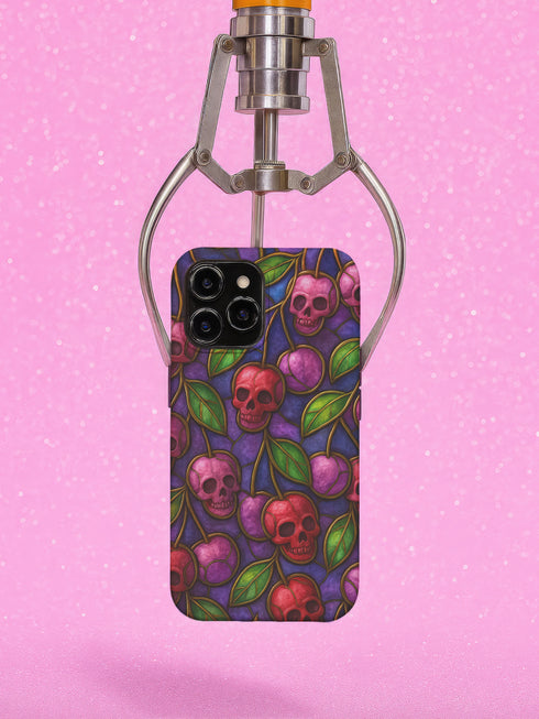 A protective phone case with a gothic cherry skull design featuring red and pink skulls blended with purple cherries and vibrant green leaves. The pattern is outlined in gold and set against a deep blue-purple stained glass background. The case has a smooth matte finish and fits various phone models with precision-cut camera openings.
