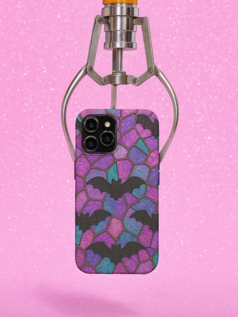 A protective phone case featuring a stained glass-style design in shades of purple, blue, and pink, with black bats flying across geometric panels outlined in gold. The case has a smooth matte finish and fits a triple-camera smartphone model.