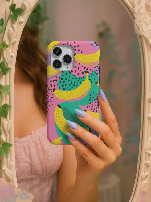 Vibrant retro phone case featuring bold yellow bananas and teal circles with black polka dots on bright pink purple background. Psychedelic fruit pattern protective phone cover with groovy 70s aesthetic perfect for iPhone Samsung Galaxy Pixel models. Colorful maximalist design with Memphis style geometric shapes dotted texture trendy tech accessory.