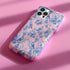 Phone case with pink background featuring blue toile print of skeletons, peacocks, owls, and roses. Victorian-inspired design with gothic elements. Dual-layer protection for various smartphone models.
