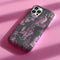 Gothic phone case featuring Victorian toile pattern in dusty rose pink on charcoal background, with skeleton unicorns, peacocks, roses, and botanical elements.