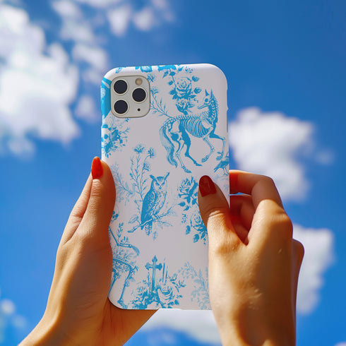 Phone case with a blue and white toile pattern featuring skeletons, owls, and floral motifs. Dual-layer protection available in glossy or matte finish.