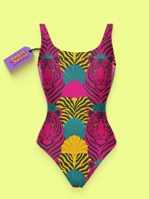 High-cut one-piece swimsuit with a bold psychedelic tiger print in hot pink, yellow, green, teal, and black. Features tiger faces, zebra stripes, and fan-shaped motifs in a maximalist retro style. Made from 81% recycled polyester and 19% LYCRA XTRALIFE. Includes cheeky fit and UPF50+ sun protection. Double layered and non-reversible. Available in sizes XS to 3XL.
