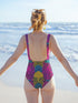 High-cut one-piece swimsuit with a bold psychedelic tiger print in hot pink, yellow, green, teal, and black. Features tiger faces, zebra stripes, and fan-shaped motifs in a maximalist retro style. Made from 81% recycled polyester and 19% LYCRA XTRALIFE. Includes cheeky fit and UPF50+ sun protection. Double layered and non-reversible. Available in sizes XS to 3XL.