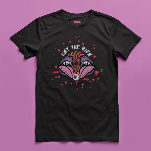 White t-shirt featuring a surreal, psychedelic design centered on the chest. An open mouth with sharp vampire-like teeth and pink tongue dominates the image. Between the teeth, a hypnotic swirling pattern in rainbow colors leads to a single eyeball on the tongue. "EAT THE RICH" is written in white above the mouth. Red paint-like splatters surround the entire design, giving it a grungy, punk aesthetic. The shirt is from the "Honey Dazed" brand.