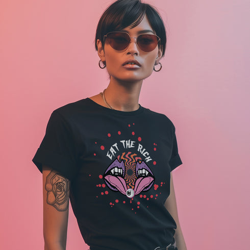 T-shirt featuring a surreal, psychedelic design centered on the chest. An open mouth with sharp vampire-like teeth and pink tongue dominates the image. Between the teeth, a hypnotic swirling pattern in rainbow colors leads to a single eyeball on the tongue. "EAT THE RICH" is written in white above the mouth. Red paint-like splatters surround the entire design, giving it a grungy, punk aesthetic. The shirt is from the "Honey Dazed" brand.