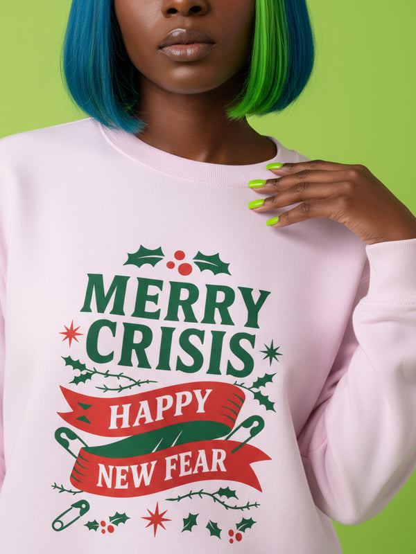 A holiday sweatshirt in pink or red with a punk and goth aesthetic. The text reads "MERRY CRISIS" and "HAPPY NEW FEAR" in a bold, gothic-style font. The design is decorated with holly leaves, berries, thorny vines, and safety pins, all arranged in a festive but alternative holiday style. This funny goth Christmas pullover is a sarcastic statement piece, perfect as dark humor apparel for the winter season.