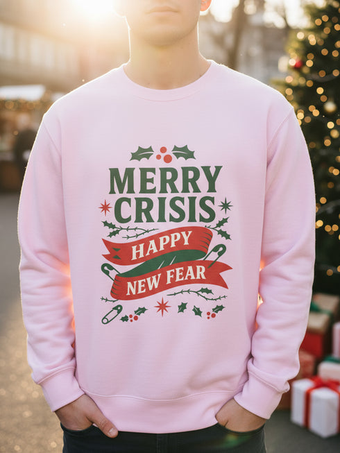 A holiday sweatshirt in pink or red with a punk and goth aesthetic. The text reads "MERRY CRISIS" and "HAPPY NEW FEAR" in a bold, gothic-style font. The design is decorated with holly leaves, berries, thorny vines, and safety pins, all arranged in a festive but alternative holiday style. This funny goth Christmas pullover is a sarcastic statement piece, perfect as dark humor apparel for the winter season.
