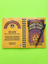 A glossy 5x7 inch spiral bound notebook featuring the phrase Inner Peace Outer Chaos in retro 70s typography. The cover showcases a vibrant psychedelic design on a mustard yellow background with a central trippy sun motif containing three mystical eyes. Below the sun, text reads Meditations, Mantras, and Meltdown Notes in bold black font. The journal has a durable black metal spiral binding and contains 150 lined pages for writing, shadow work, or daily planning.