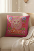 Maximalist throw pillow for the Leo zodiac sign featuring a centralized lion head medallion with an ornate mane mimicking embroidered textures. The background is a vibrant hot pink, accented by ochre, rust, and lime green floral motifs and blue flowers in each corner. The pillow is square with a hidden zipper and a polyester insert. This high-contrast design is a perfect fit for dopamine decor, whimsigoth apartments, or any eclectic home looking for a bold astrology-inspired statement piece.