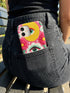 Maximalist phone case with a vibrant hot pink background featuring a faux crochet knit texture illusion. The design includes a large yellow crescent moon with a green eye in the top right, a central white cloud with a green eye and red lashes, and green mountain peaks at the bottom. Red flowers and pink swirling mist accent the scene.