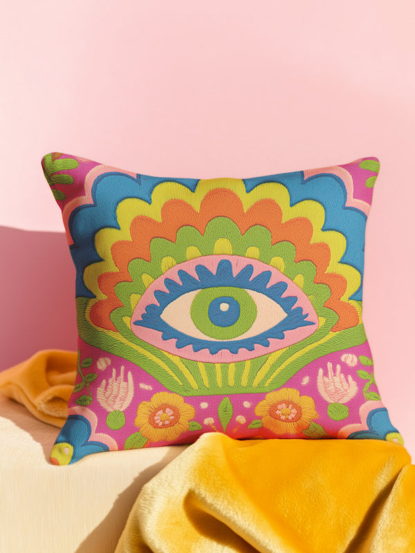 Polyester faux embroidered pillow cover featuring a bold maximalist evil eye design with a colorful folk-art inspired pattern. The front print includes a central blue, green, and pink eye surrounded by scalloped floral shapes, rainbow-like arches, leafy details, and bright decorative flowers in pink, orange, yellow, blue, and green. Soft square pillow cover with a textured woven-look print. Available in 18x18 or 22x22 inches.