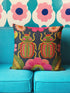 Navy blue square throw pillow cover featuring two vibrant beetles in a symmetrical design. The beetles have jewel-toned wings in emerald green and hot pink, rendered in a faux-embroidery texture style that mimics stitched threads. The background is a deep midnight blue with stylized floral accents. The texture is a smooth digital print on spun polyester. Ideal for maximalist homes and entomolgy art.