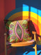 Black square pillow cover with a central eye medallion set inside a pink almond shaped mandorla. The psychedelic design surrounds the eye with red floral motifs, green leaves, and radiant orange and yellow sunburst rays. The smooth, linen-feel polyester print mimics high fidelity embroidery texture with no raised stitching. Divine feminine and sacred feminine eye pillow case, a feminist maximalist and whimsigoth cushion cover on a bold high-contrast black ground.
