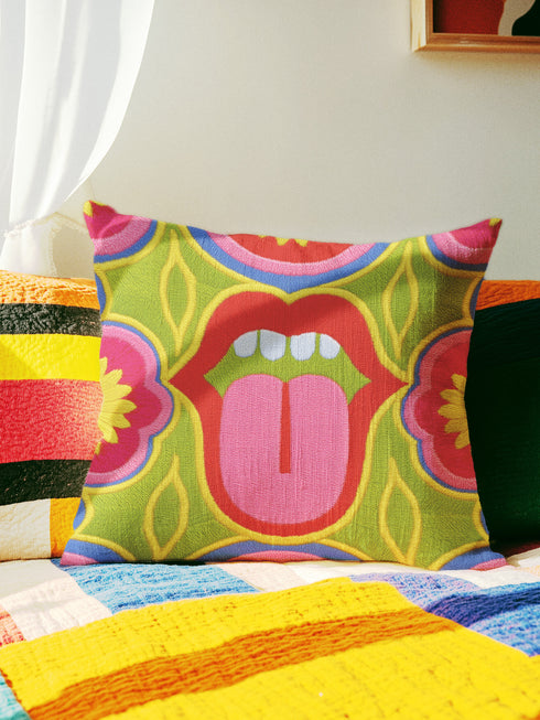 A square decorative throw pillow cover featuring a bold, symmetrical pop art design of an open mouth with bright red lips, white teeth, and a pink tongue sticking out. The central graphic is set against a lime green background surrounded by abstract geometric and floral shapes in vibrant hues of pink, yellow, and cornflower blue. The fabric has a visible premium linen-like woven texture. The colorful retro illustration is printed on both sides of the pillowcase.