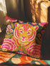 Square decorative throw pillow cover featuring a vibrant, maximalist illustration of a walking tiger surrounded by blooming pink peonies and green foliage. The design is set against a deep teal-charcoal background and mimics the texture of vintage hand embroidery with a faux-stitch printed effect. The style blends Junglecore, Chinoiserie, and Whimsigoth aesthetics. The fabric is a durable, linen-textured spun polyester. The tiger is orange, gold, and black; flowers are magenta pink.