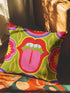 A square decorative throw pillow cover featuring a bold, symmetrical pop art design of an open mouth with bright red lips, white teeth, and a pink tongue sticking out. The central graphic is set against a lime green background surrounded by abstract geometric and floral shapes in vibrant hues of pink, yellow, and cornflower blue. The fabric has a visible premium linen-like woven texture. The colorful retro illustration is printed on both sides of the pillowcase.