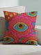 A square decorative throw pillow with a premium linen-feel texture. The design is a repeating pattern of stylized evil eyes on a dusty blue background. Each eye is rendered in turquoise, olive green, and black, and is framed by vibrant hot pink petals with radiating gold lines, resembling a flower or sunburst. The all-over print is colorful and has a visual texture that mimics embroidery. The pillow has a clean, knife-edge finish and a double-sided design, showcasing a bold, psychedelic pattern.