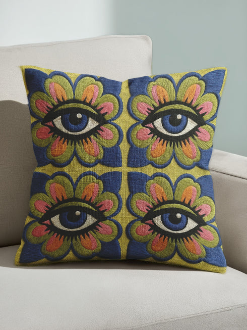 Square double-sided throw pillow cover featuring a vibrant faux embroidery design. Four stylized blue eyes sit inside retro pink, green, and orange floral shapes against a textured chartreuse yellow-green background. Made from premium faux linen polyester with a clean hidden zipper edge. This maximalist dopamine decor cushion cover is shown perfectly flat, highlighting the bold surrealist trompe-l'œil graphic print. Available in 18x18 or 22x22 inches.