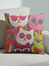 Square throw pillow cover packed with a dense repeating pattern of cat faces in hot pink, lime green, purple, and white, every cat wearing oversized retro sunglasses. Wavy psychedelic bands of orange, yellow, and green weave through the background. The flat 2D print mimics heavy textured crewel needlepoint on a smooth, linen-feel fabric. Reversible same design front and back with a hidden zipper. Funky maximalist cat decor and quirky apartment warming gift, available in 18 by 18 inch and 22 by 22 inch, cove