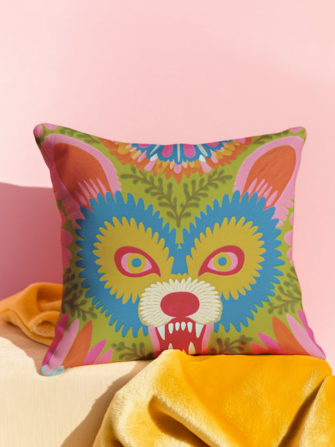 A square throw pillow cover featuring a vibrant, symmetrical illustration of an angry opossum face. The design mimics the texture of folk art embroidery but is a smooth flat print on faux linen fabric. The possum features teal blue fur, bright yellow eyes with pink pupils, and a red nose, bearing sharp white teeth in a hiss or scream. The background is a mossy green with pink and orange floral accents surrounding the animal. The style is maximalist, eclectic, colorful, and feral core aesthetic.