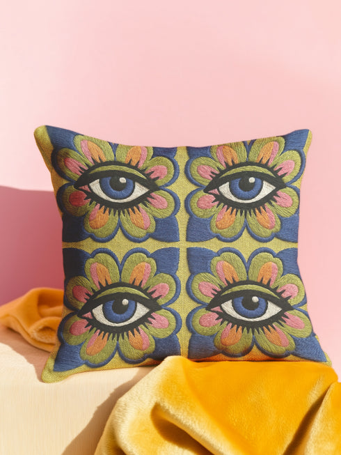 Square double-sided throw pillow cover featuring a vibrant faux embroidery design. Four stylized blue eyes sit inside retro pink, green, and orange floral shapes against a textured chartreuse yellow-green background. Made from premium faux linen polyester with a clean hidden zipper edge. This maximalist dopamine decor cushion cover is shown perfectly flat, highlighting the bold surrealist trompe-l'œil graphic print. Available in 18x18 or 22x22 inches.