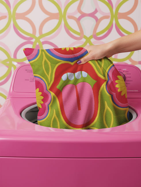 A square decorative throw pillow cover featuring a bold, symmetrical pop art design of an open mouth with bright red lips, white teeth, and a pink tongue sticking out. The central graphic is set against a lime green background surrounded by abstract geometric and floral shapes in vibrant hues of pink, yellow, and cornflower blue. The fabric has a visible premium linen-like woven texture. The colorful retro illustration is printed on both sides of the pillowcase.