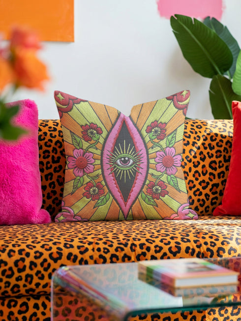 Black square pillow cover with a central eye medallion set inside a pink almond shaped mandorla. The psychedelic design surrounds the eye with red floral motifs, green leaves, and radiant orange and yellow sunburst rays. The smooth, linen-feel polyester print mimics high fidelity embroidery texture with no raised stitching. Divine feminine and sacred feminine eye pillow case, a feminist maximalist and whimsigoth cushion cover on a bold high-contrast black ground.