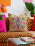 Black square pillow cover with a central eye medallion set inside a pink almond shaped mandorla. The psychedelic design surrounds the eye with red floral motifs, green leaves, and radiant orange and yellow sunburst rays. The smooth, linen-feel polyester print mimics high fidelity embroidery texture with no raised stitching. Divine feminine and sacred feminine eye pillow case, a feminist maximalist and whimsigoth cushion cover on a bold high-contrast black ground.
