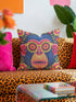 quare throw pillow cover with a faux embroidery 2D print of a stylized monkey face in large round yellow sunglasses with red flower lenses. The ape has electric blue fur with a hot pink brow and nose, on a navy background scattered with hot pink, yellow, and red flowers and green leaves. The print mimics raised stitching while staying flat and smooth, and shows on both sides. Cover only, available in 18 by 18 inch and 22 by 22 inch sizes.