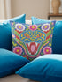 Square throw pillow cover with a faux embroidery 2D print of a stylized folk-art serpent with a blue head, yellow swirl markings, red eyes, white fangs, and an open red mouth. It is surrounded by pink, purple, and white flowers with yellow centers and green leaves on a deep blue background. The print mimics raised stitching while staying flat and smooth, and shows on both sides. Cover only, available in 18 by 18 inch and 22 by 22 inch sizes.