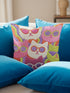 Square throw pillow cover packed with a dense repeating pattern of cat faces in hot pink, lime green, purple, and white, every cat wearing oversized retro sunglasses. Wavy psychedelic bands of orange, yellow, and green weave through the background. The flat 2D print mimics heavy textured crewel needlepoint on a smooth, linen-feel fabric. Reversible same design front and back with a hidden zipper. Funky maximalist cat decor and quirky apartment warming gift, available in 18 by 18 inch and 22 by 22 inch, cove