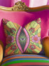 Black square pillow cover with a central eye medallion set inside a pink almond shaped mandorla. The psychedelic design surrounds the eye with red floral motifs, green leaves, and radiant orange and yellow sunburst rays. The smooth, linen-feel polyester print mimics high fidelity embroidery texture with no raised stitching. Divine feminine and sacred feminine eye pillow case, a feminist maximalist and whimsigoth cushion cover on a bold high-contrast black ground.