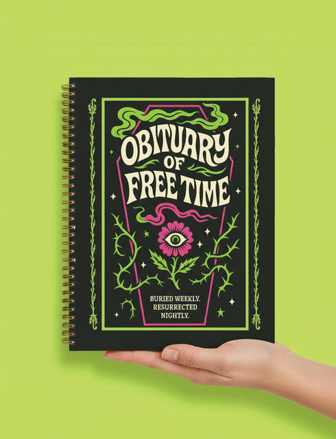 A black hardcover spiral planner. The cover features a vibrant, coffin-shaped frame in lime green and magenta pink, bordered by thorny vines. Inside the frame, the title "Obituary of Free Time" is written in a psychedelic 70s-style font. Below the title, a pink flower with a single green eyeball at its center blooms from a thorny stem. The planner is bound with a gold metal wire-o spiral on the left side. The design has a spooky cute, gothic floral aesthetic.