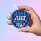 Round embroidered iron-on patch featuring "MAKE ART NOT WAR" text with blue floral design. Navy blue background with light blue border, white cream lettering, and small yellow-centered blue flowers. 3-inch circular twill fabric patch perfect for jackets, backpacks, denim, and clothing customization. Anti-war peace activist feminist punk alternative accessory for creative counterculture gift giving.