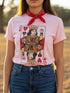 A centralized graphic design of a Queen of Hearts playing card on a cream or pink unisex t-shirt. The Queen is depicted in a maximalist folk art style, holding a heart-topped scepter and a raised fist in a gesture of solidarity. The word "RESIST" is visible on her crown and a central banner in ochre and true red tones. The layout is a centralized medallion style with rust and ochre accents and a playing card border.