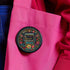 Round black pinback button with vibrant Mexican folk art-inspired embroidery design featuring red, yellow, blue and teal flowers surrounding a gold book spine with "Read Banned Books" text. Literary protest accessory with glossy finish and safety pin backing, available in 2" and 3" sizes.