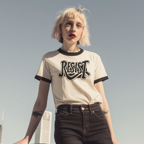 Heather gray ringer t-shirt with black contrast trim on the collar and sleeve cuffs. The front features a bold black graphic of an open mouth with the phrase "EAT THE RICH" in capital letters, integrated into the teeth. Surrounding the design are hand-drawn lines and accents, giving it a raw, punk-inspired aesthetic. The t-shirt has a vintage-inspired fit, made from soft cotton fabric with a slightly relaxed silhouette. The high-contrast black and gray design enhances the statement-making impact of the grap