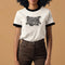 Heather gray ringer t-shirt with black contrast trim on the collar and sleeve cuffs. The front features a bold black graphic of an open mouth with the phrase "EAT THE RICH" in capital letters, integrated into the teeth. Surrounding the design are hand-drawn lines and accents, giving it a raw, punk-inspired aesthetic. The t-shirt has a vintage-inspired fit, made from soft cotton fabric with a slightly relaxed silhouette. The high-contrast black and gray design enhances the statement-making impact of the grap