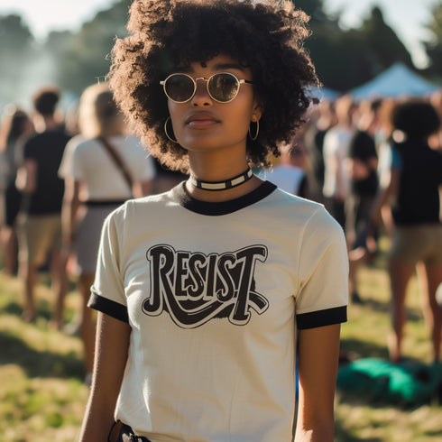 Heather gray ringer t-shirt with black contrast trim on the collar and sleeve cuffs. The front features a bold black graphic of an open mouth with the phrase "EAT THE RICH" in capital letters, integrated into the teeth. Surrounding the design are hand-drawn lines and accents, giving it a raw, punk-inspired aesthetic. The t-shirt has a vintage-inspired fit, made from soft cotton fabric with a slightly relaxed silhouette. The high-contrast black and gray design enhances the statement-making impact of the grap