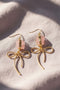 Earrings featuring pink rose quartz stones with 14k gold-plated brass bow designs, offering a sweet and sophisticated touch.