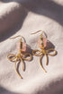 Earrings featuring pink rose quartz stones with 14k gold-plated brass bow designs, offering a sweet and sophisticated touch.