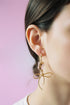 Earrings featuring pink rose quartz stones with 14k gold-plated brass bow designs, offering a sweet and sophisticated touch.