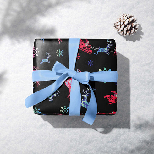Christmas wrapping paper with a black background featuring colorful, stylized reindeer and Santa's sleigh designs. The reindeer and sleigh silhouettes are filled with skeletal patterns in shades of blue, pink, and red. Multicolored snowflakes in various sizes are scattered throughout. The paper has a whimsical, slightly gothic aesthetic that blends traditional holiday imagery with a unique, edgy twist.